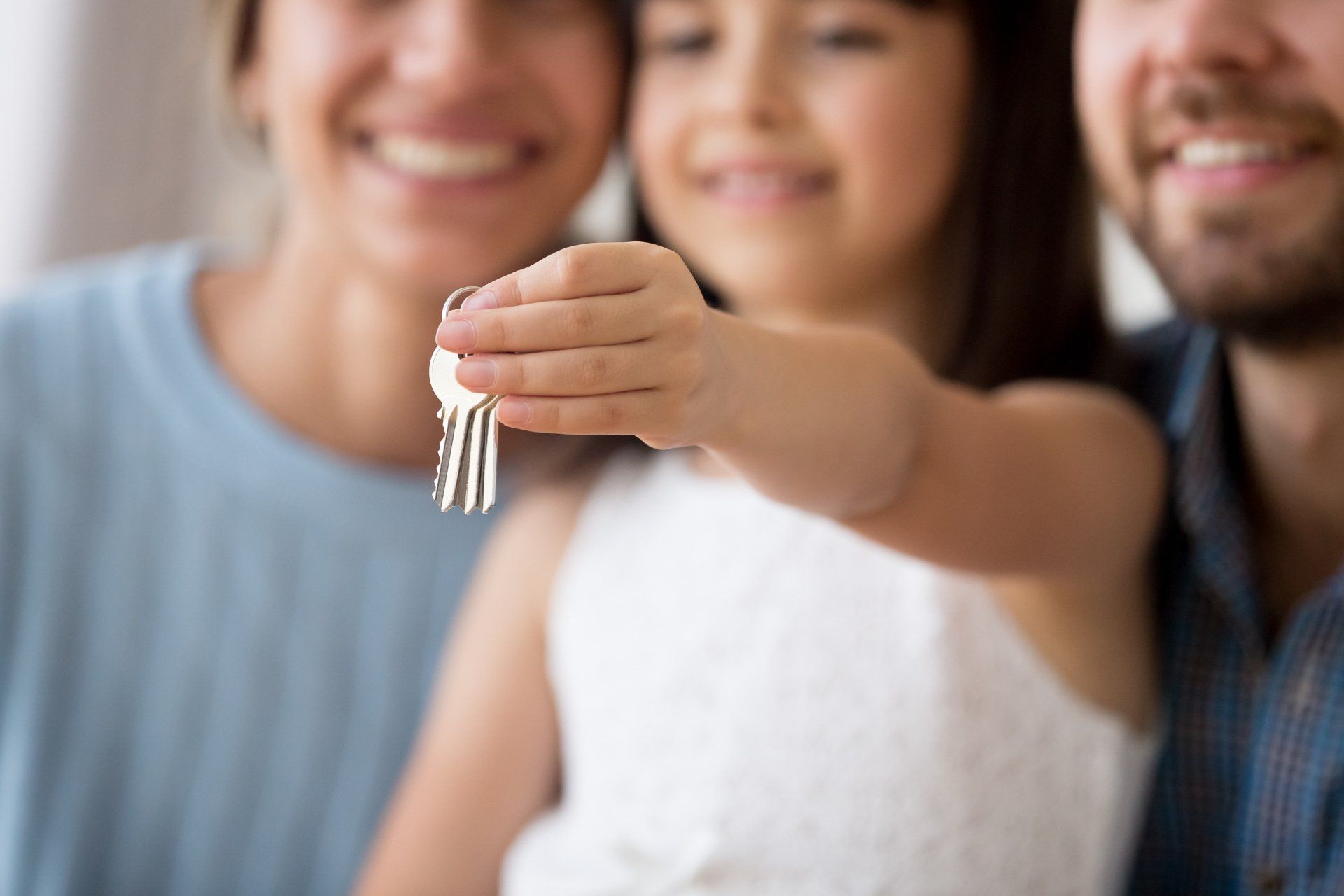 A little girl is holding a bunch of keys in front of her parents.