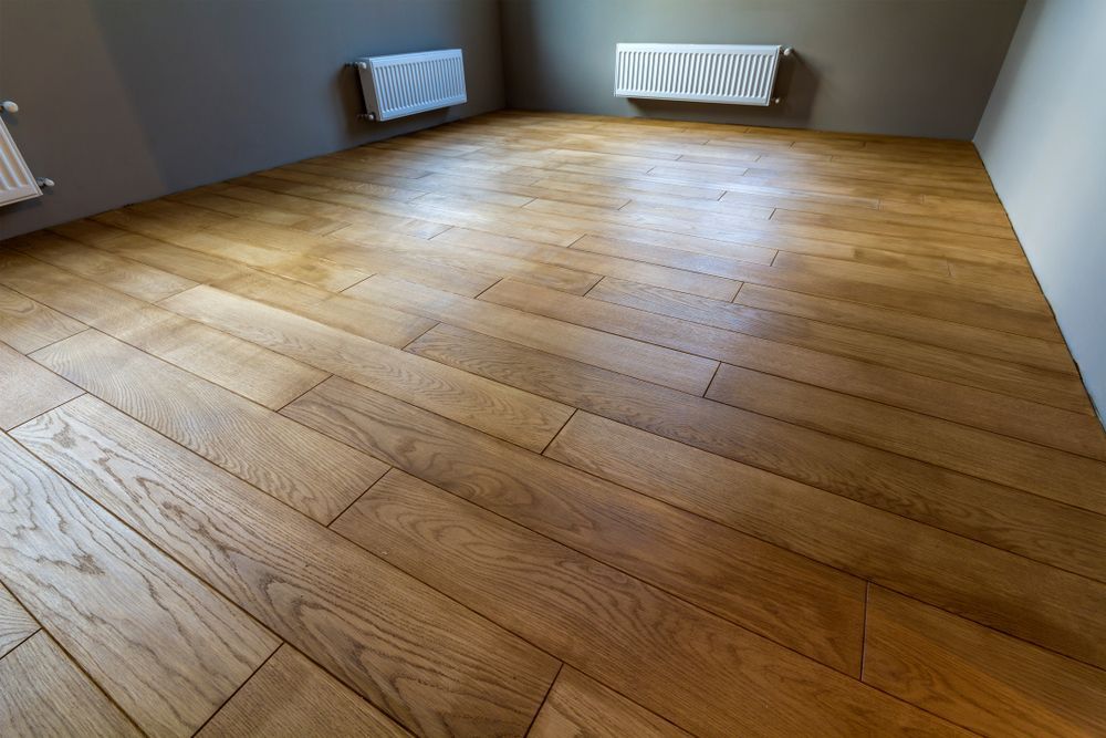 Wooden floor in a room, with diagonal plank pattern. Radiators on gray walls. Bright natural light. — Toowoomba Polished Floors in Clifton, QLD