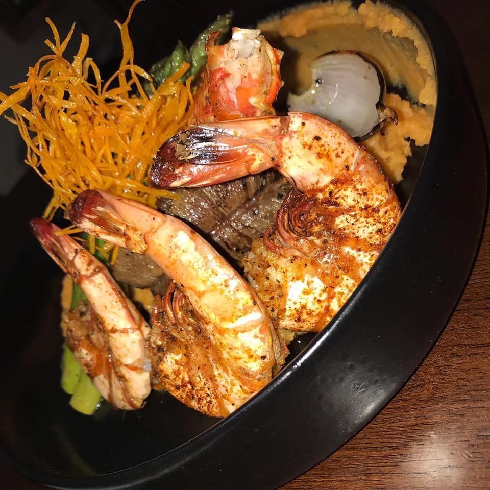 A black bowl filled with shrimp and meat on a table