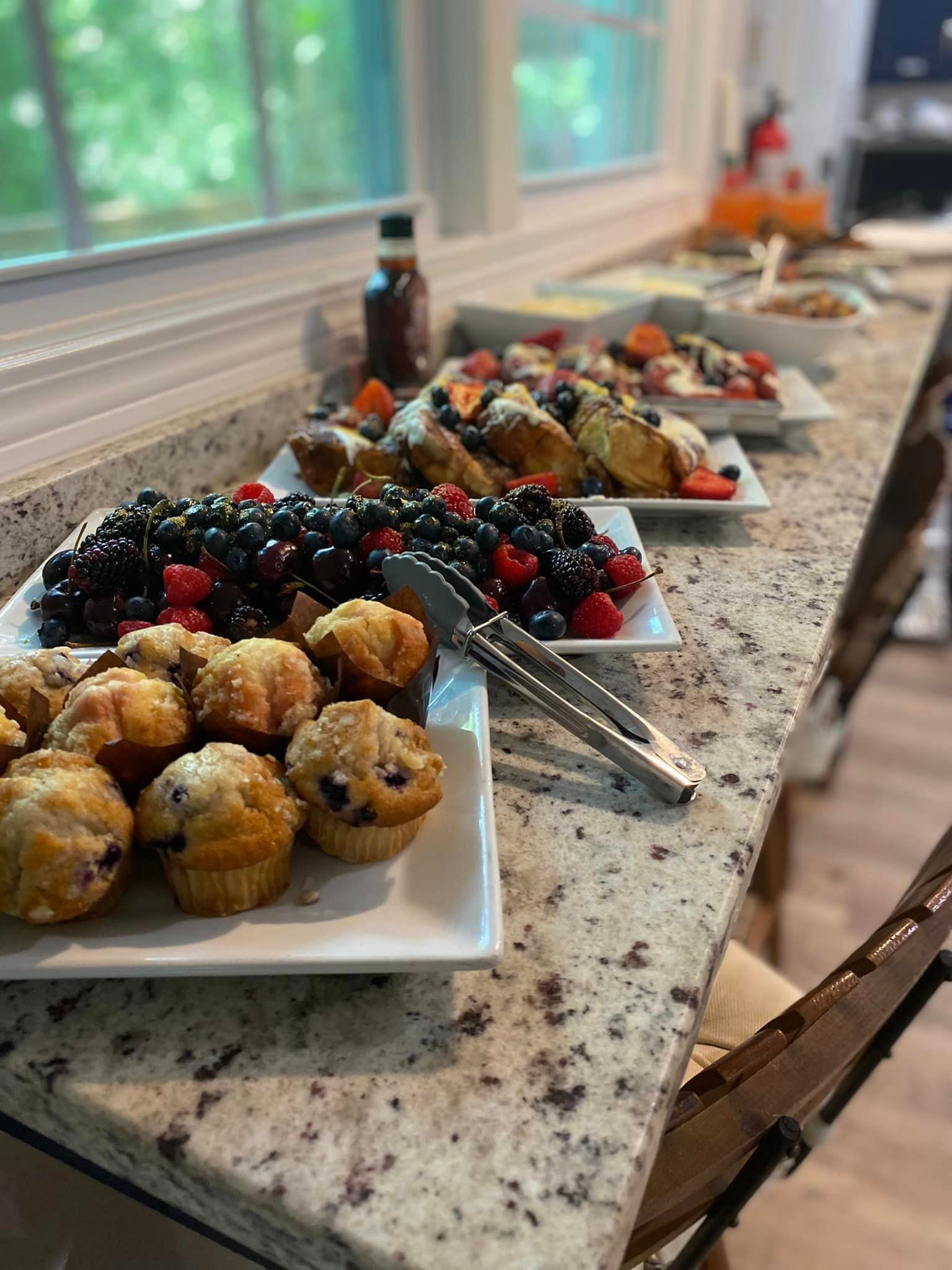 A buffet table with plates of food and tongs on it.