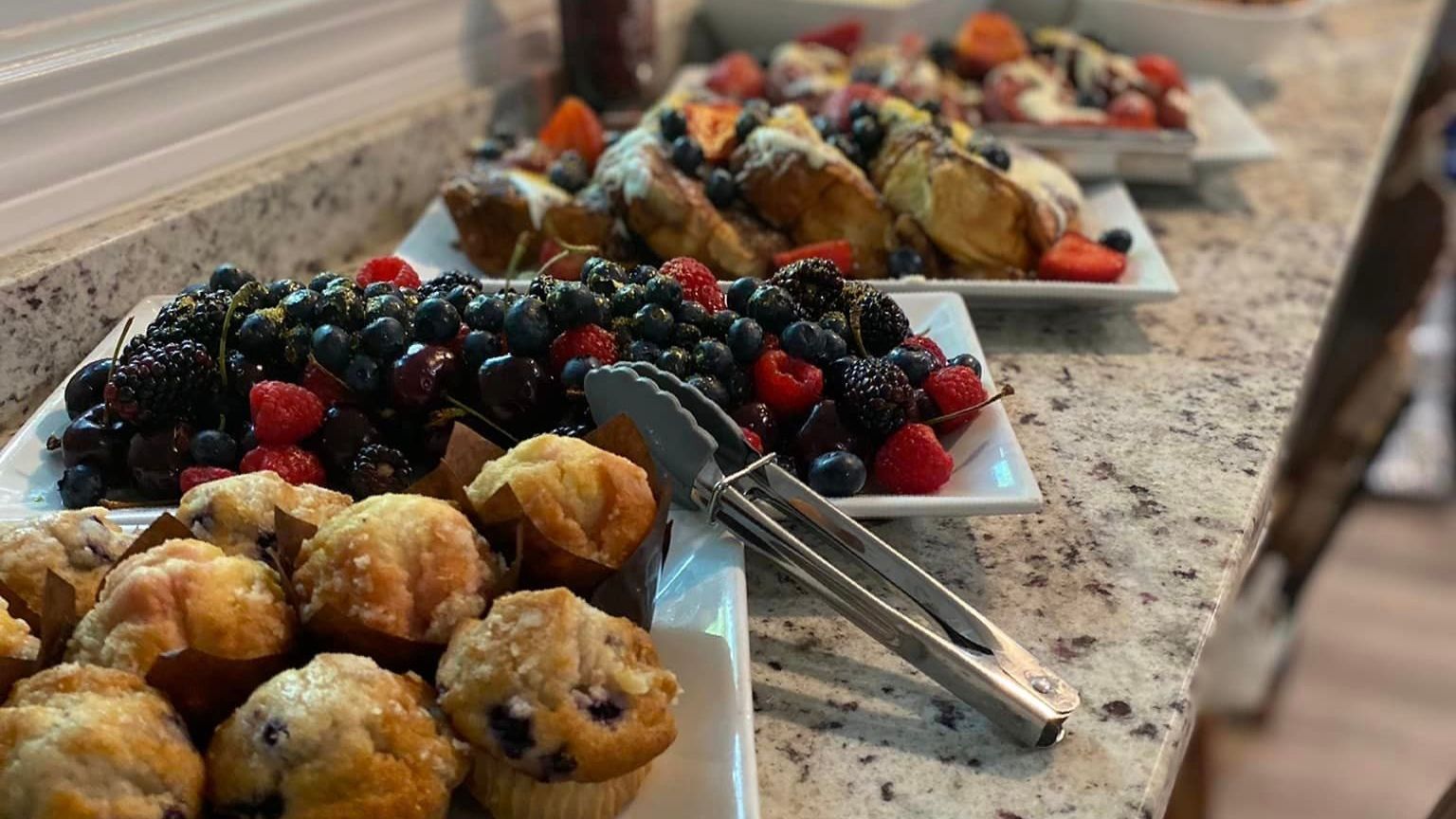 Tray of assorted pastries and berries on a buffet table with serving tongs
