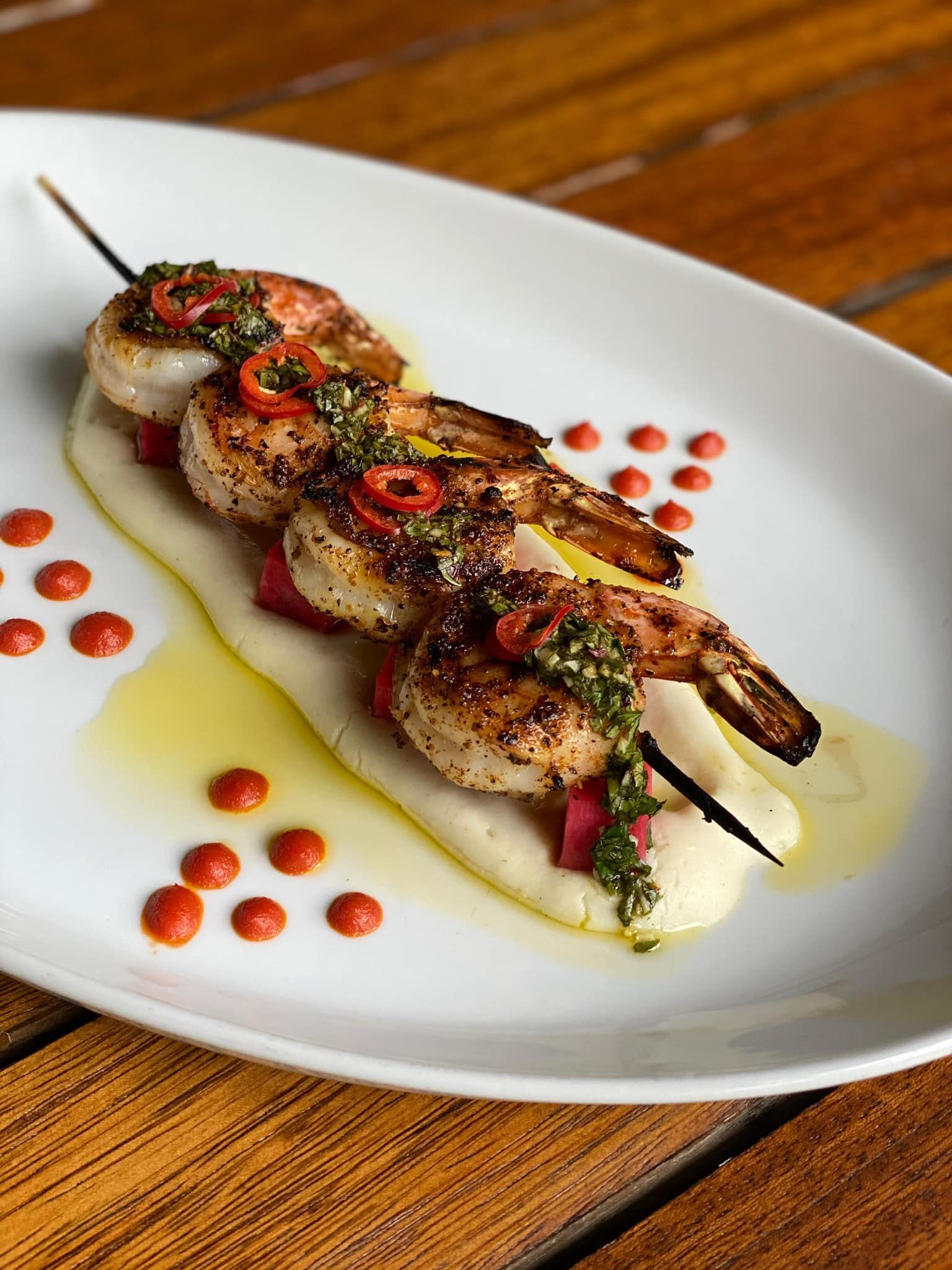 A white plate topped with shrimp and mashed potatoes on a wooden table.