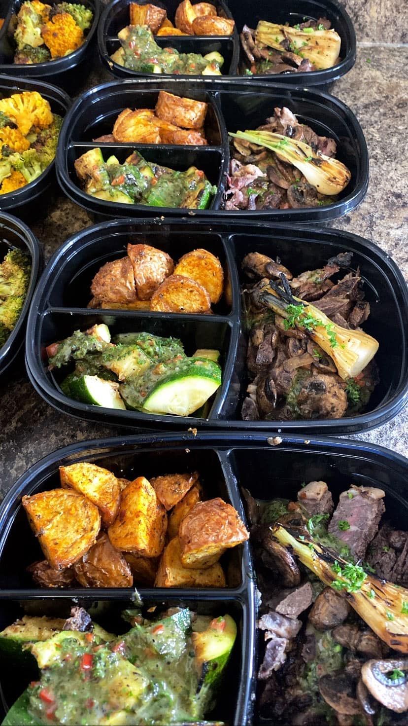 A bunch of plastic containers filled with different types of food on a table.