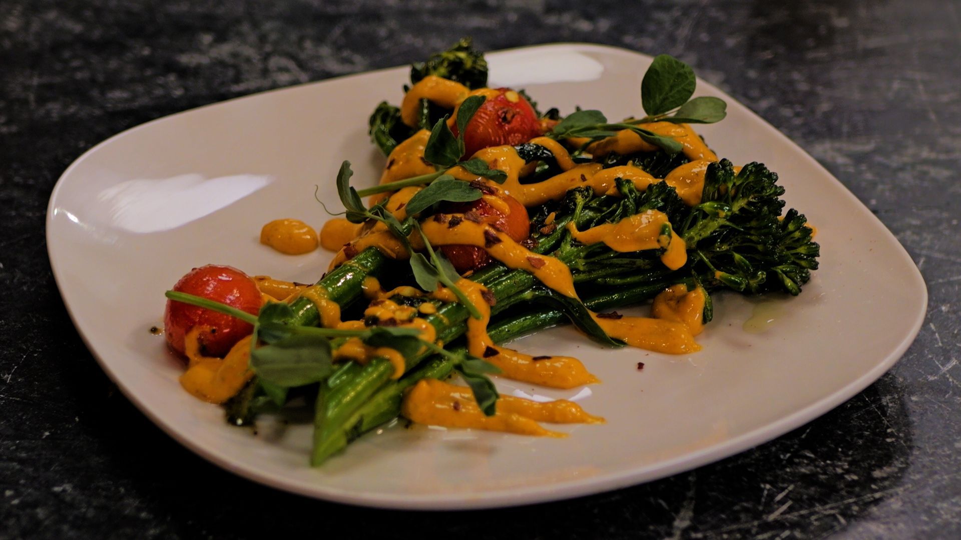 Plated sautéed vegetables with orange sauce on a white dish