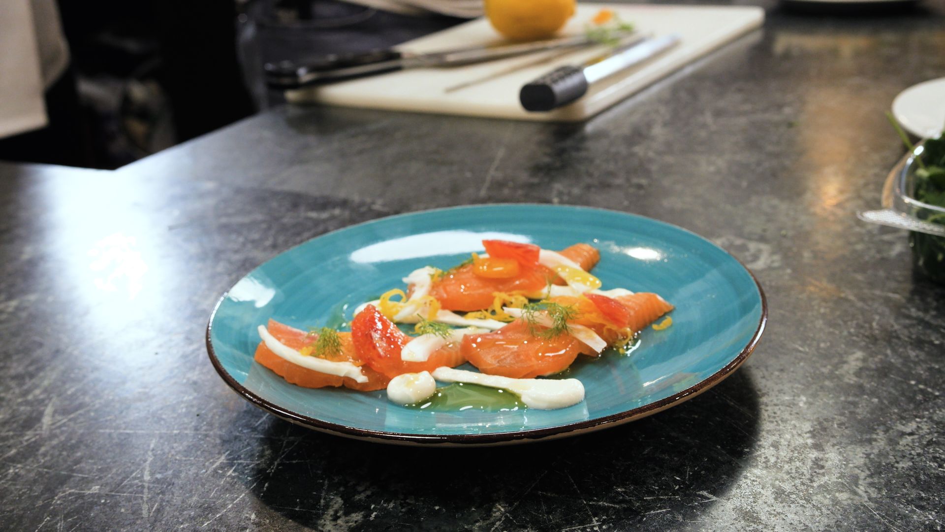 Blue plate with plated salad of tomatoes and mozzarella on a dark countertop