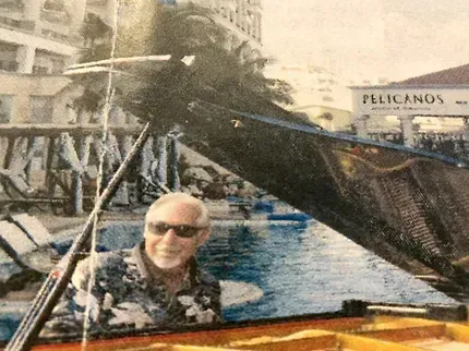 Bob Barry is sitting at a piano in front of a pelican's restaurant