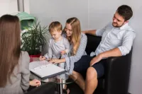 People reviewing a home insurance form at a table with documents and a pen