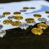 Gold and silver coins scattered across a printed financial chart on a desk