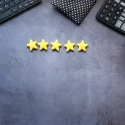 Five yellow stars on a gray desk, with a keyboard and notebook in the corners