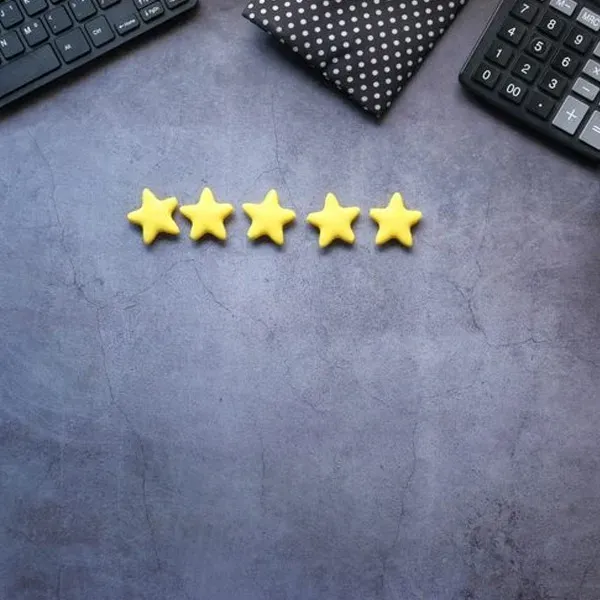 Five yellow stars on a gray desk, with a keyboard and notebook in the corners