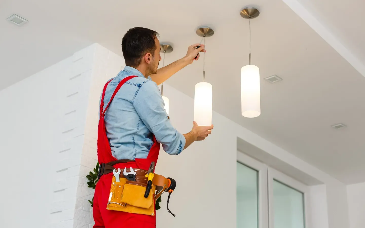 Service of Knights LLC - A man is installing a light fixture on the ceiling of a room.