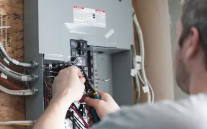 Service of Knights LLC - A man is working on an electrical box with a pair of pliers.
