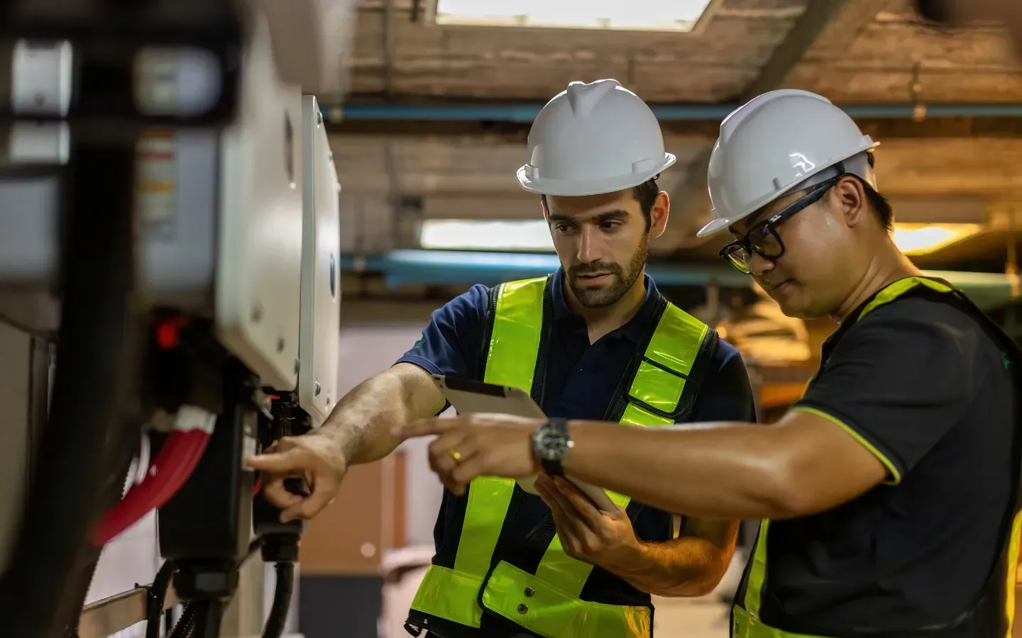 Service of Knights LLC - Two men wearing hard hats and safety vests are working on a machine.