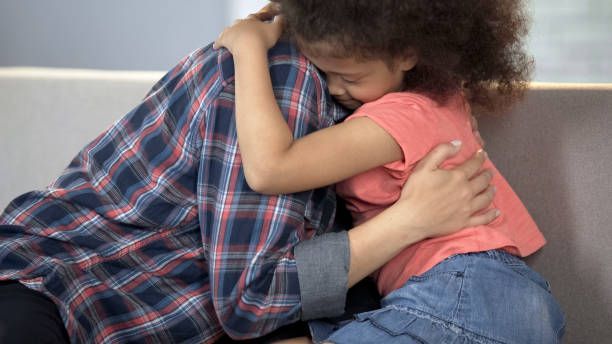 A little girl is hugging a man on a couch.