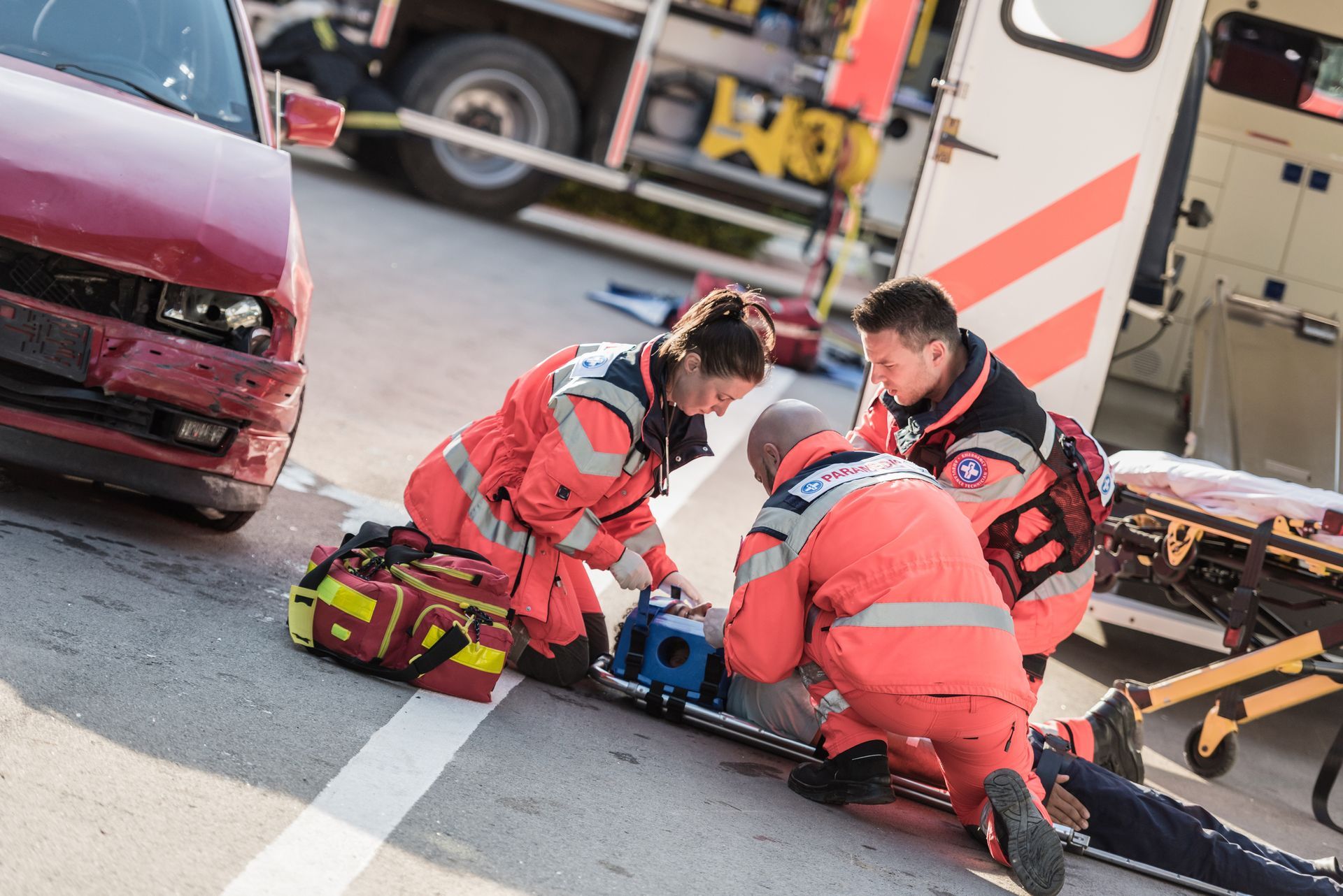 A group of paramedics are helping a man on a stretcher after a car accident.