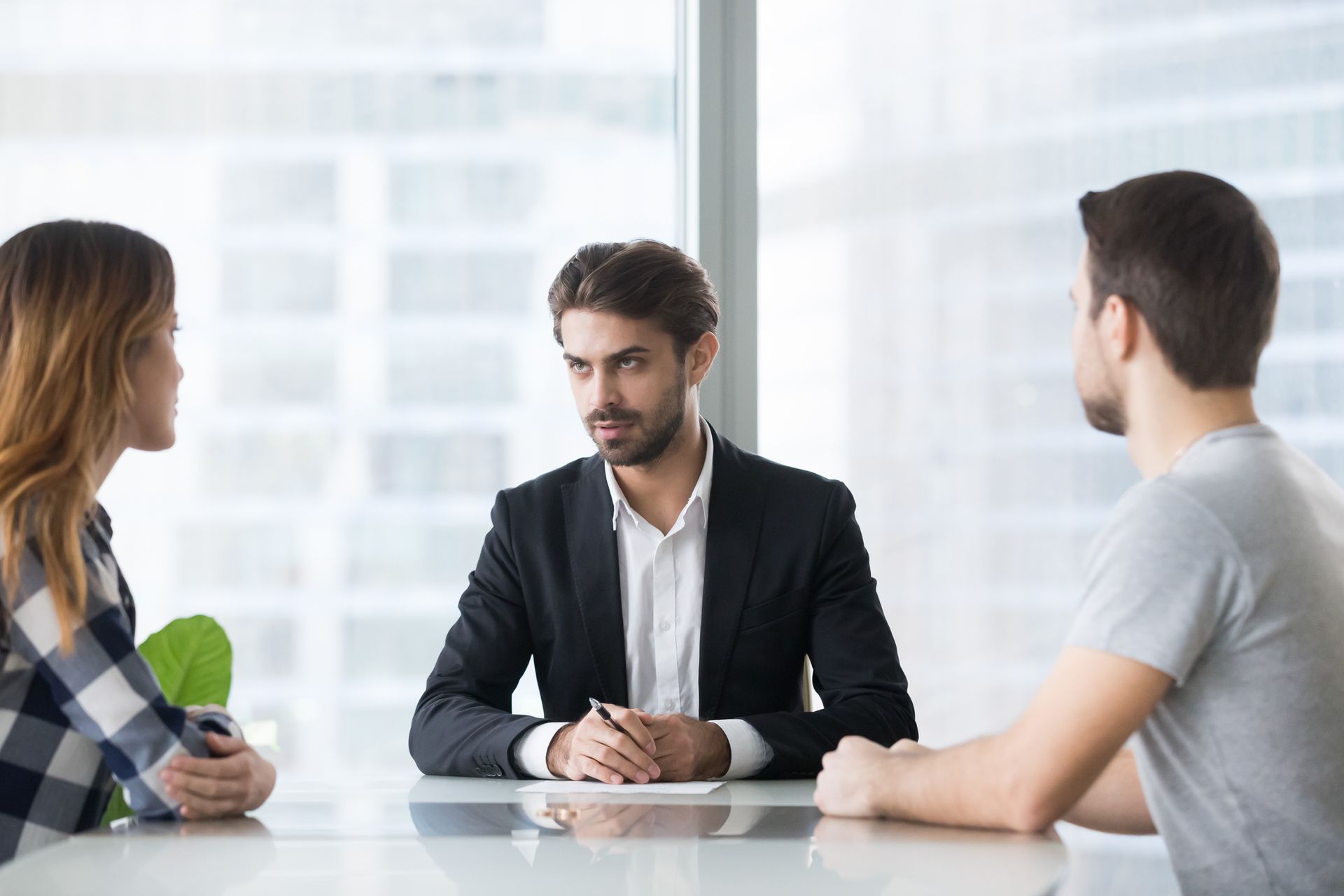 A man in a suit is sitting at a table with two people.