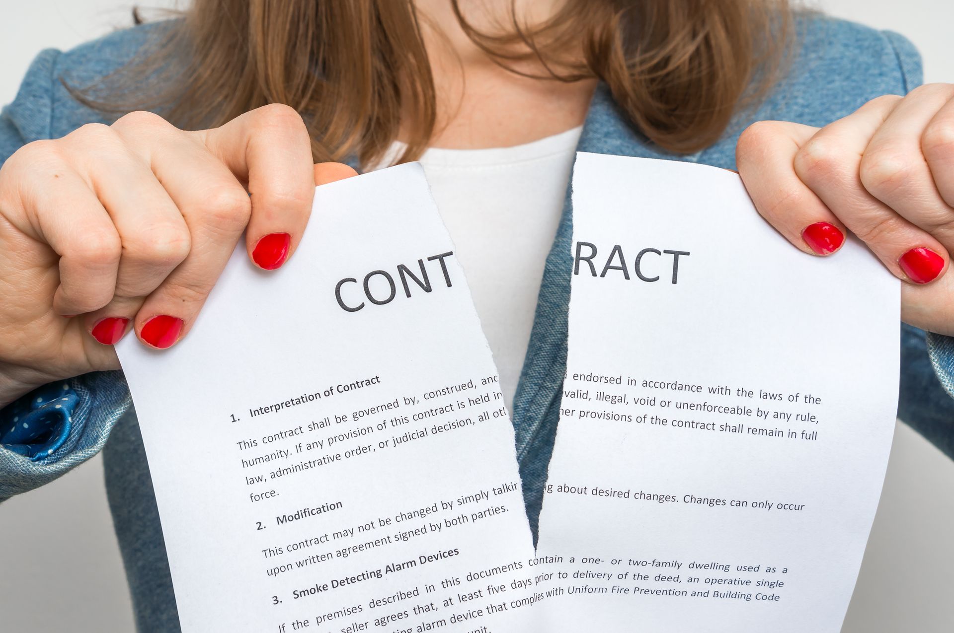 A woman is ripping up a contract in half.