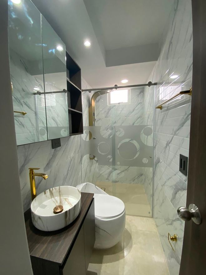 Elegante dormitorio beige con una cama bien hecha, iluminación cálida en la pared, revestimiento de listones de madera y una lámpara colgante.