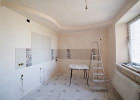 Habitación blanca sin terminar con una mesa, una escalera y una ventana durante la reforma.