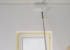 Fregona o palo montado en el techo, apoyado contra una pared blanca encima de una puerta.