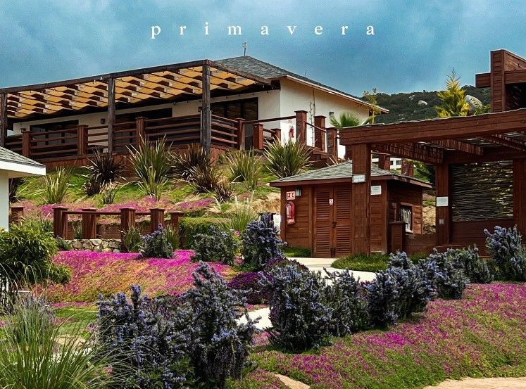 Casa de estilo español con pérgolas de madera y exuberantes flores de jardín rosas, moradas y verdes.