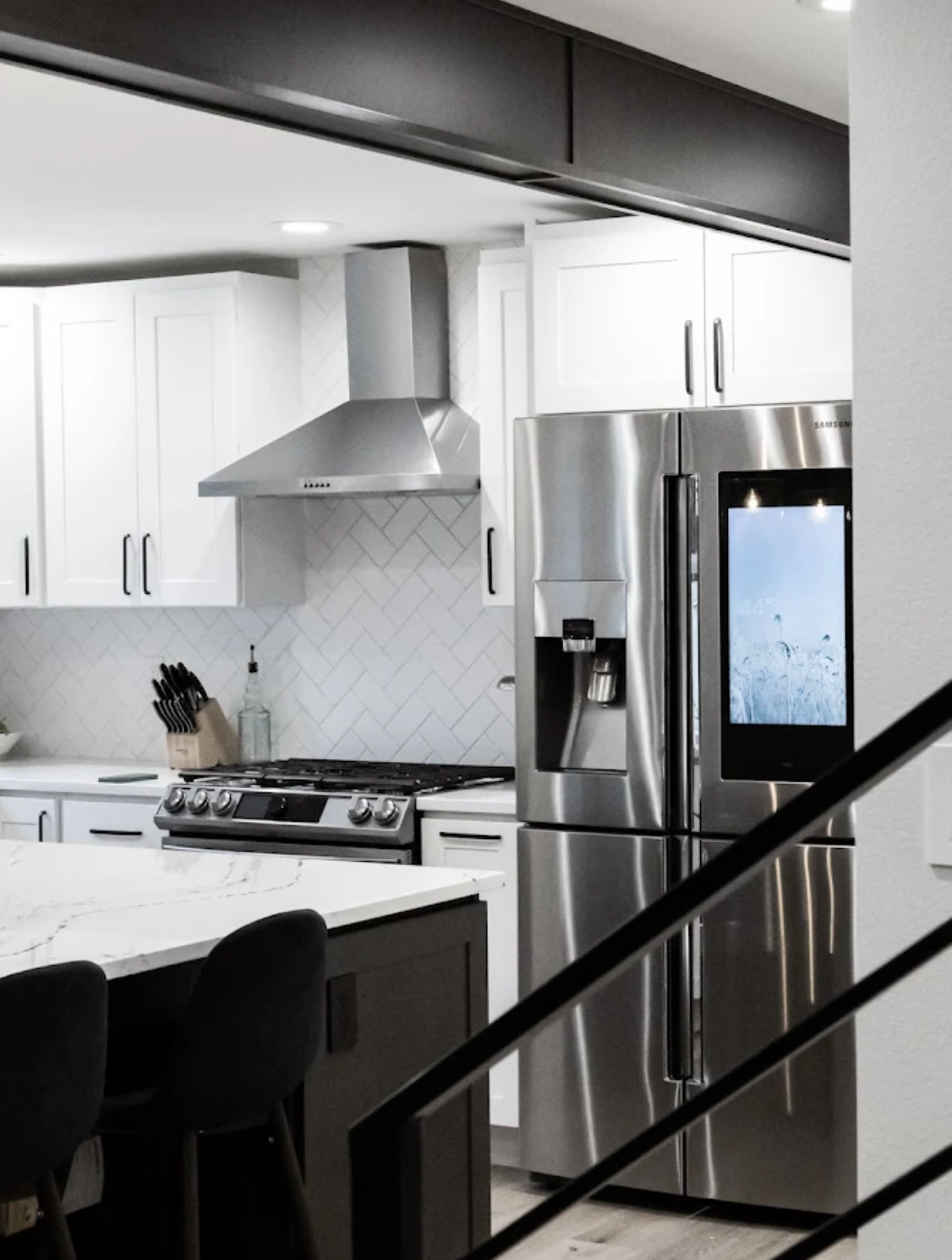 Modern kitchen with white cabinets, stainless steel appliances, and a dark island.