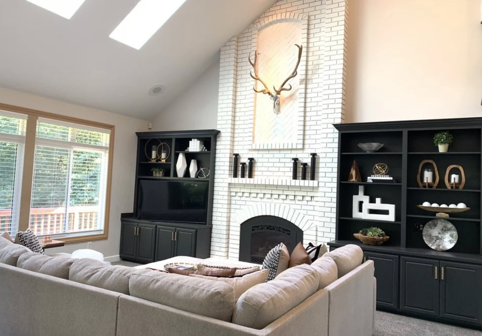 Living room with vaulted ceiling, white brick fireplace, sectional sofa, and built-in black cabinets.