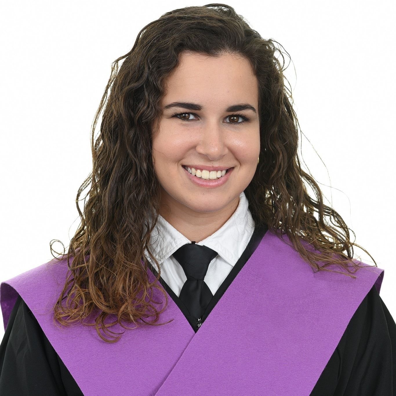 Mujer con cabello castaño y rizado en traje de graduación sonriendo.