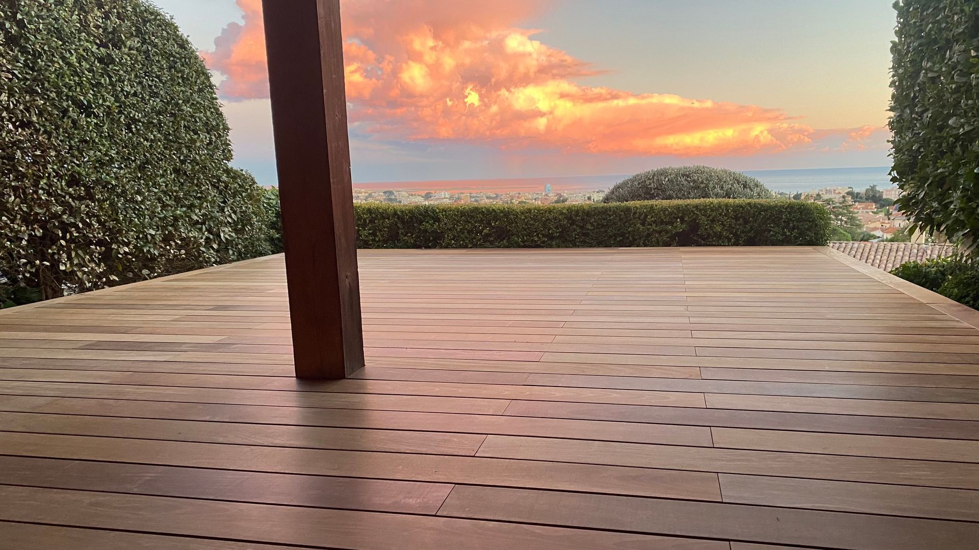 Une terrasse en bois avec un coucher de soleil en arrière-plan.