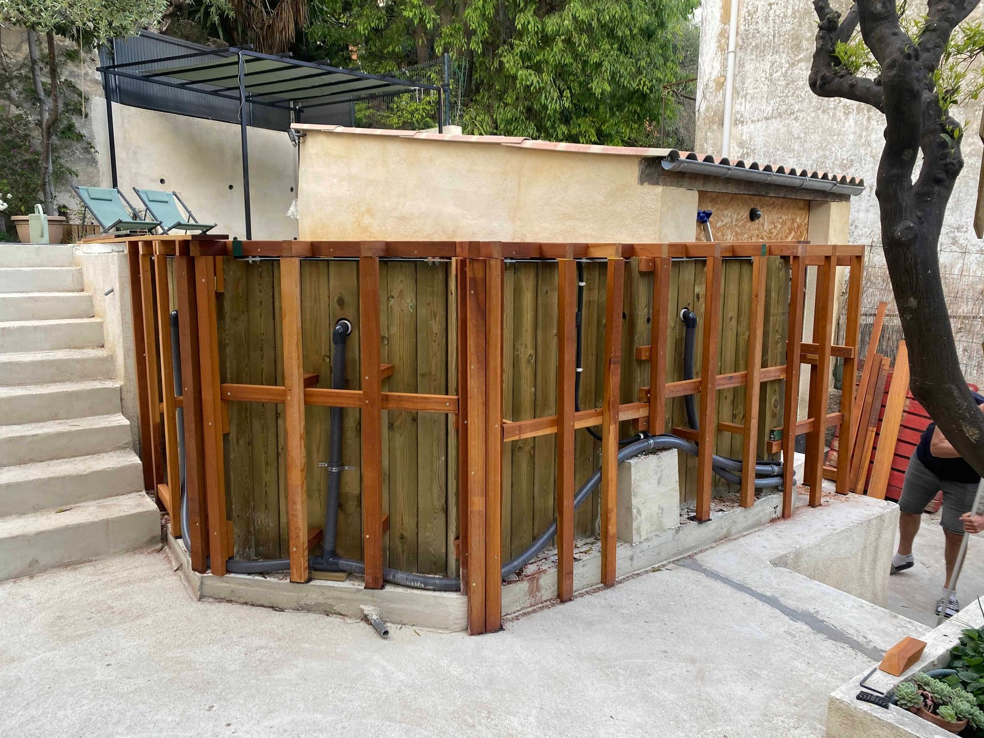 Une clôture en bois est en cours de construction autour d'une piscine.