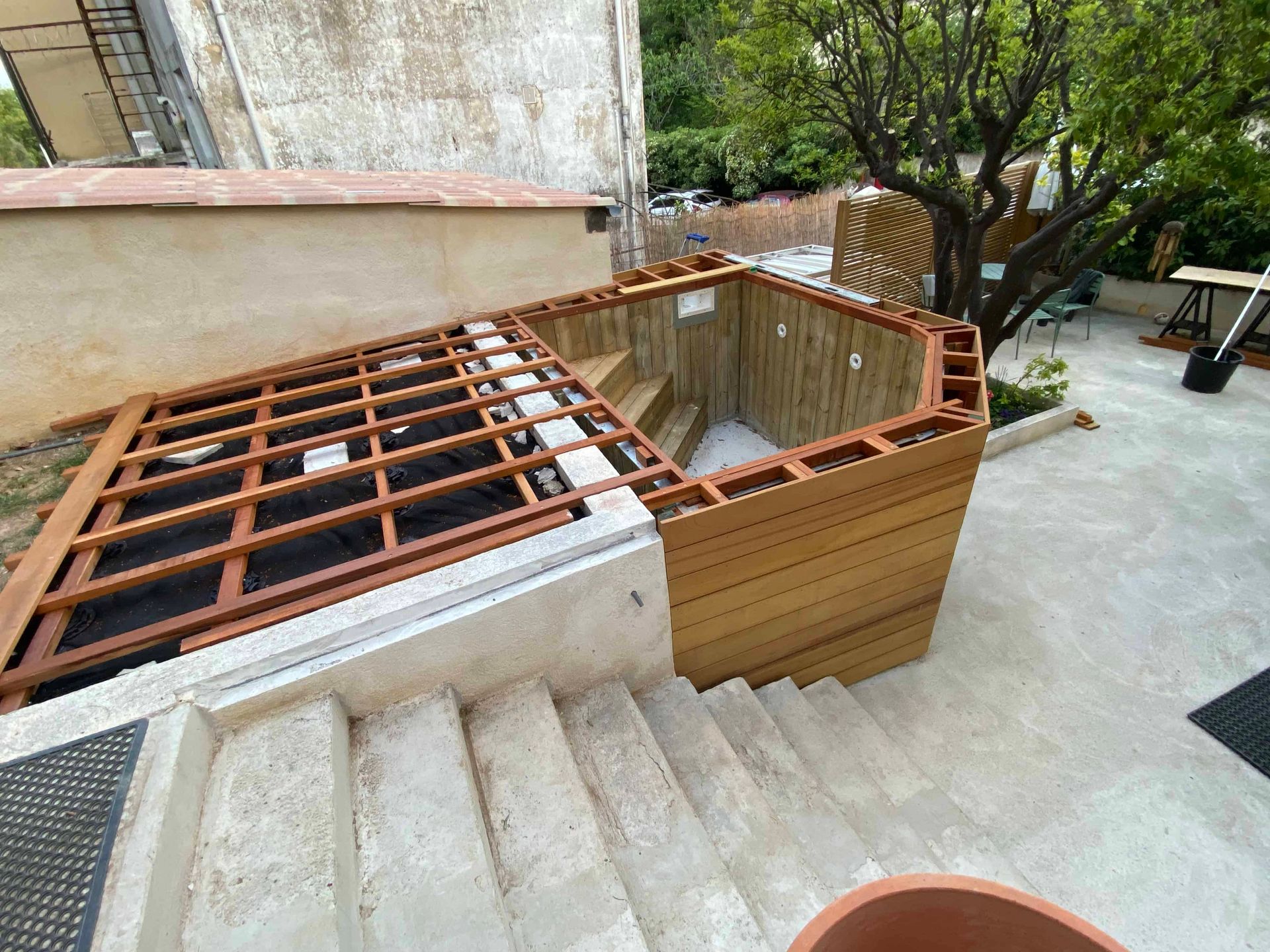Une terrasse en bois est en cours de construction à côté d'un escalier.