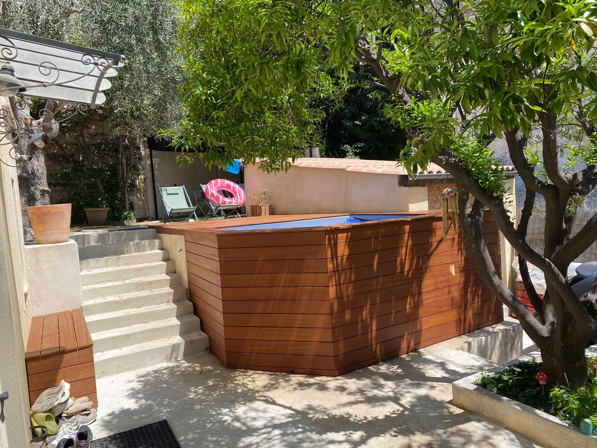 Une clôture en bois entoure une piscine dans une cour.