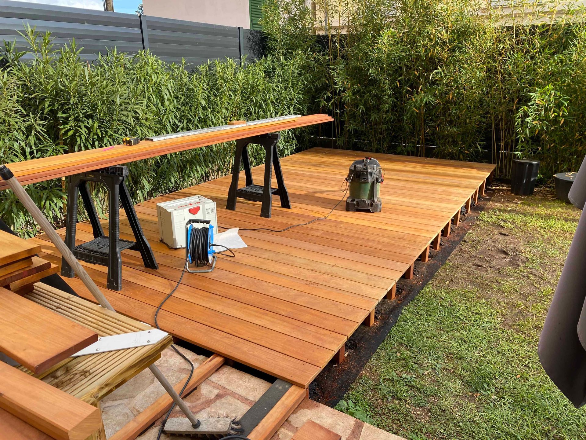Une terrasse en bois est en cours de construction dans une cour.
