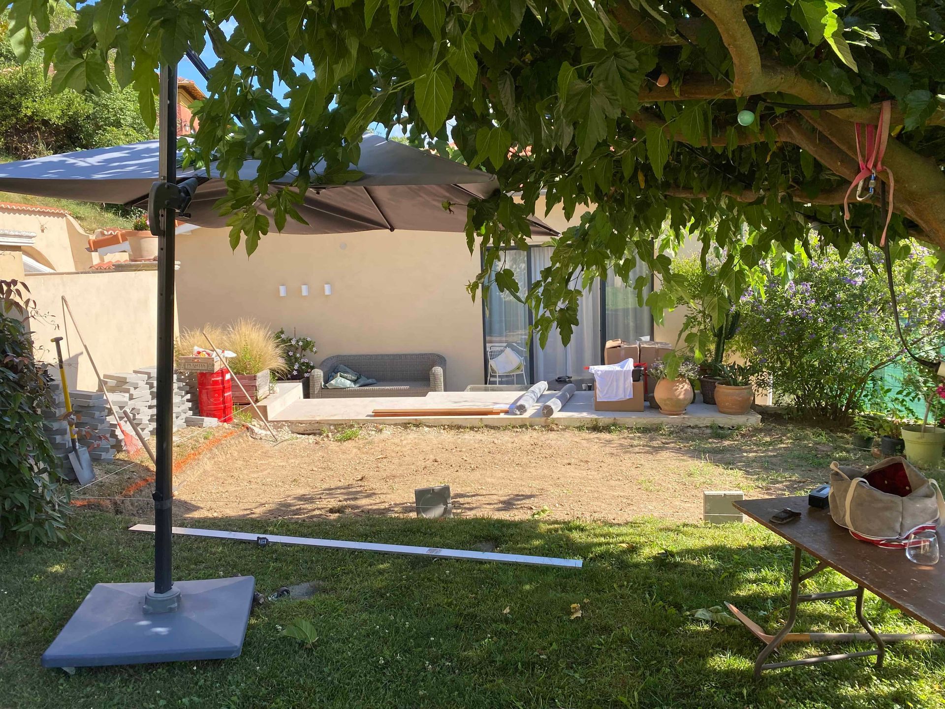 Un grand parapluie est posé sous un arbre dans une cour arrière.