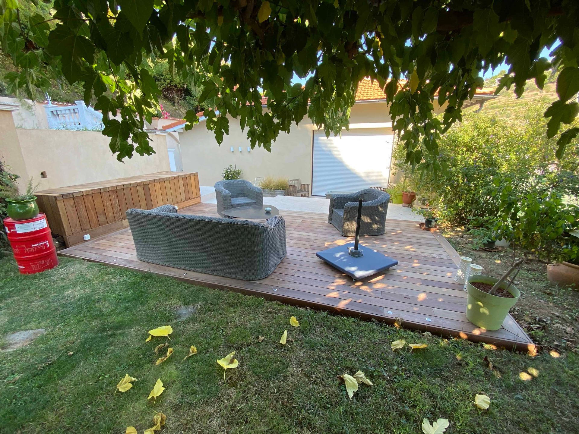 Une terrasse en bois avec un canapé, des chaises et un parasol dans une cour arrière.