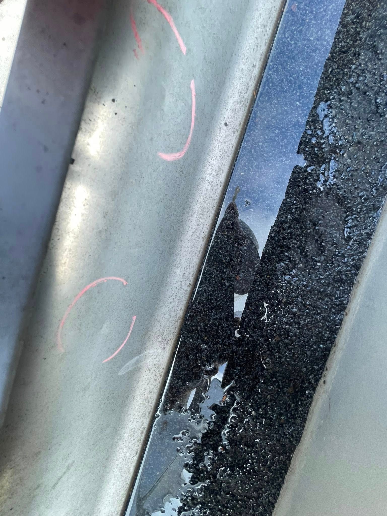 Close-up of a gray metal surface beside a black damaged strip with a small white tear.