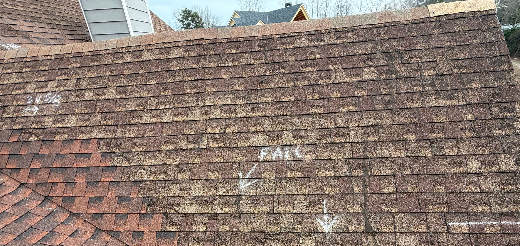 Weathered brown shingled roof with a white ladder at the left edge and a patch of red shingles below
