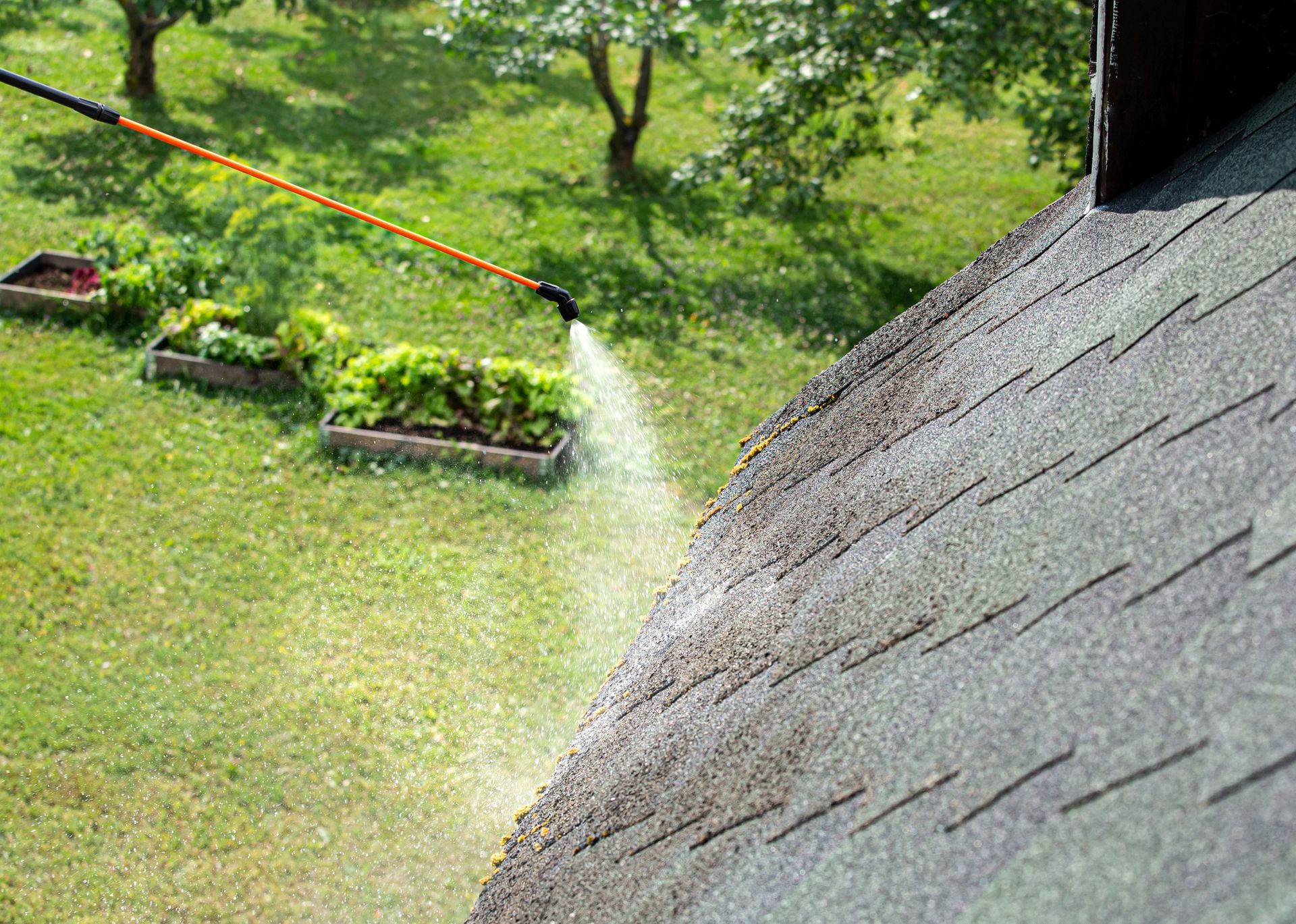 A person is spraying a roof with a hose.