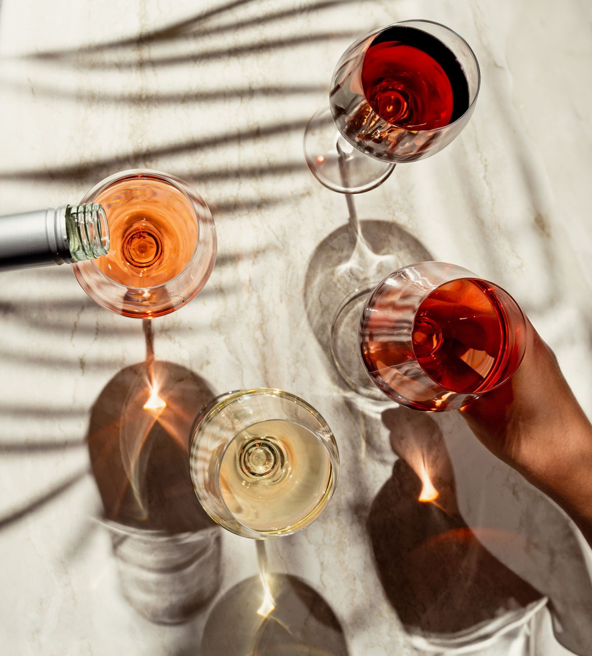 A person is pouring wine into wine glasses on a table.