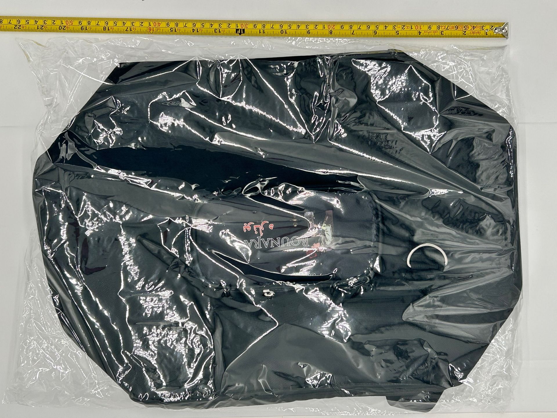 Black backpack with a clear front pocket holding a brown cylindrical item.
