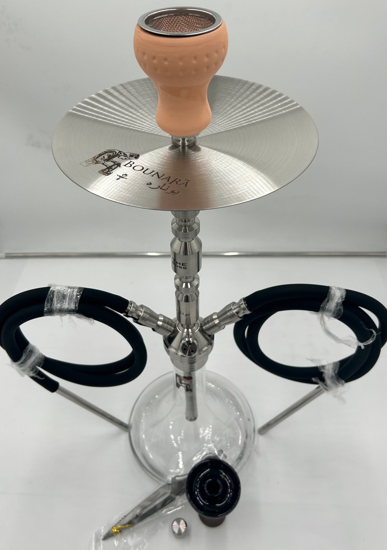 Hookah with peach bowl, silver tray, clear base, and black hoses on a white background