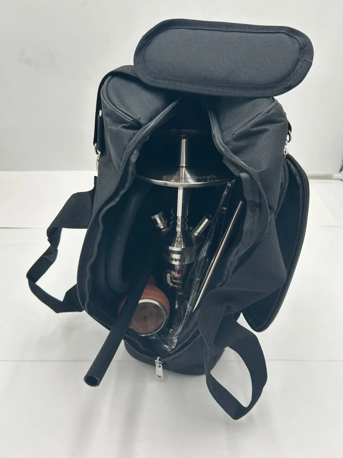 Black backpack standing open on a white surface, with padded shoulder straps and side pockets.