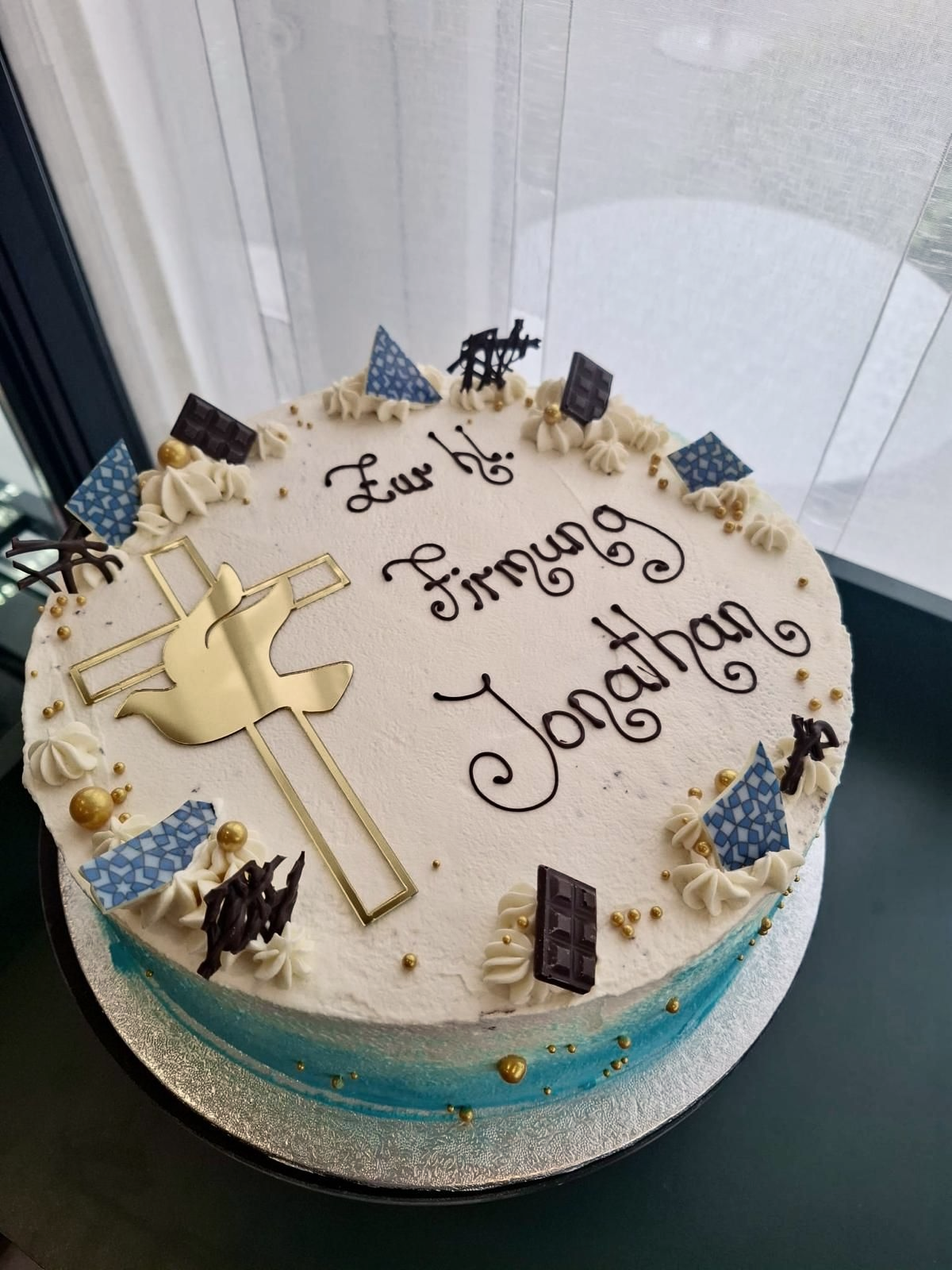Torte zur Konfirmation verziert mit der Aufschrift „Zur hl.  Firmung“, einer goldenen Taube und blauen Akzenten.