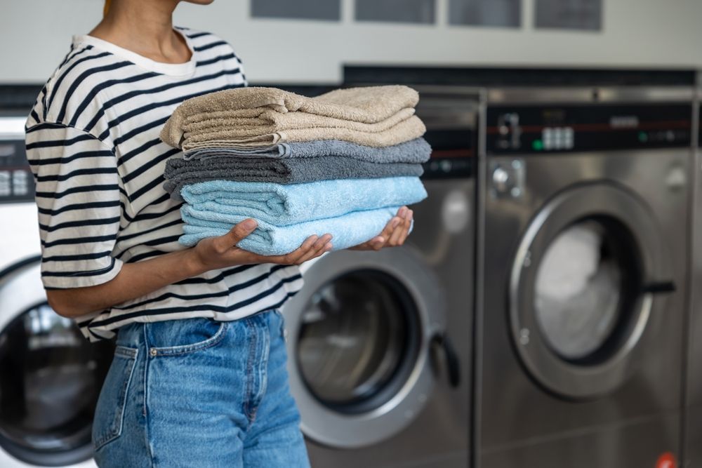 Woman holding a stack of neatly folded laundry