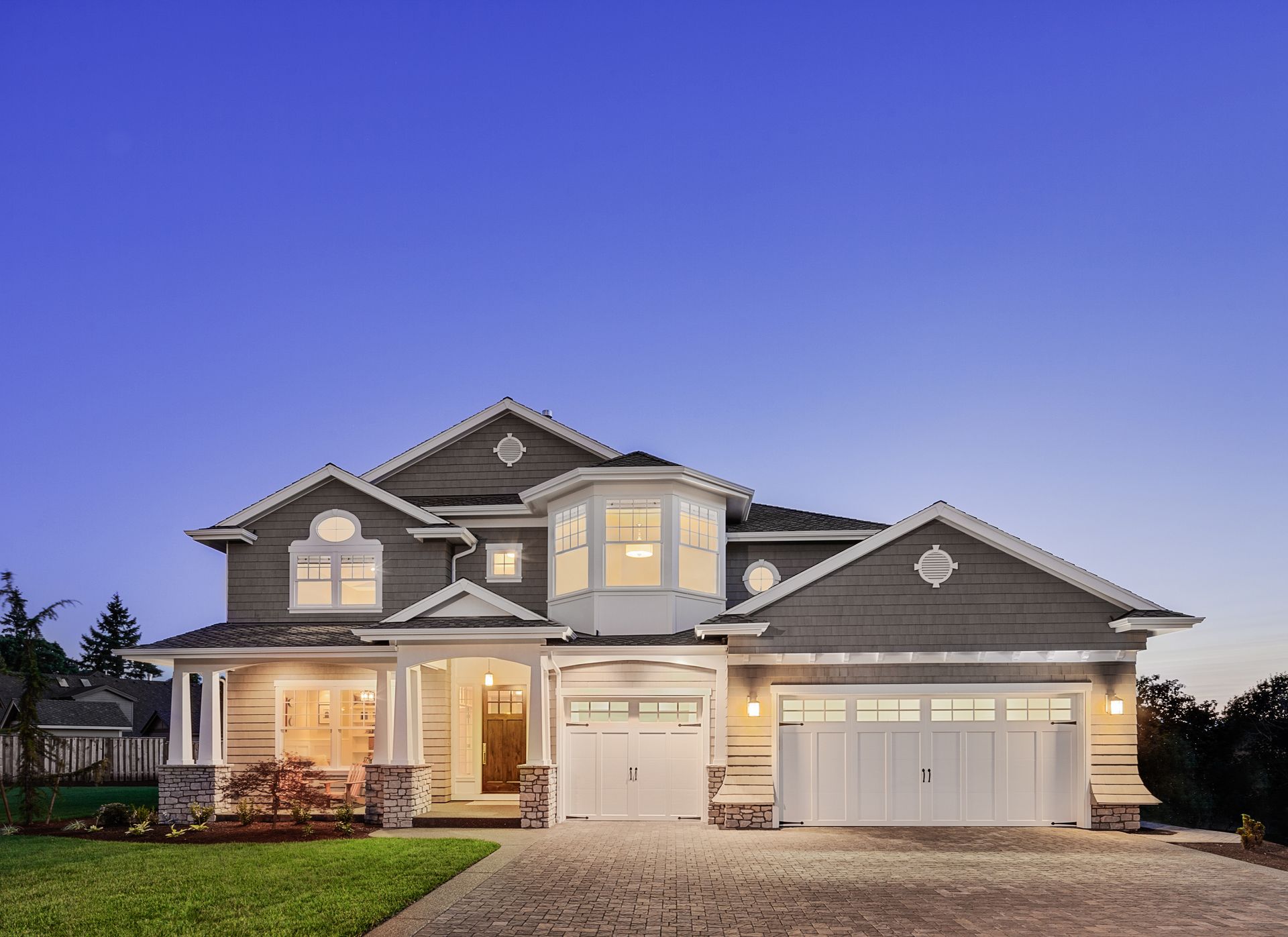 A large house with a large garage is lit up at night.