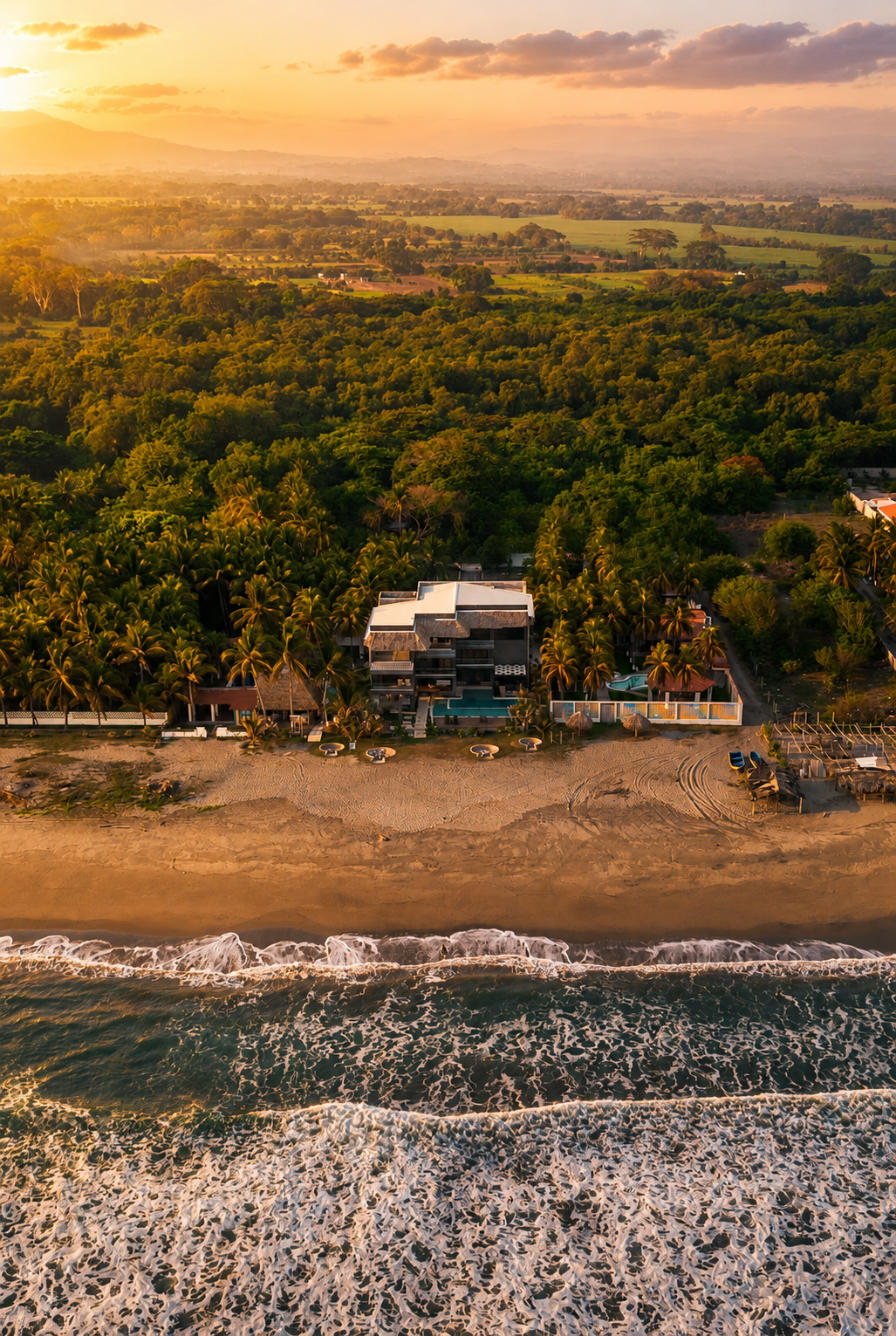 Vista aérea de una playa tropical con olas, un denso bosque verde y edificios al atardecer en cardedeu cangrejera