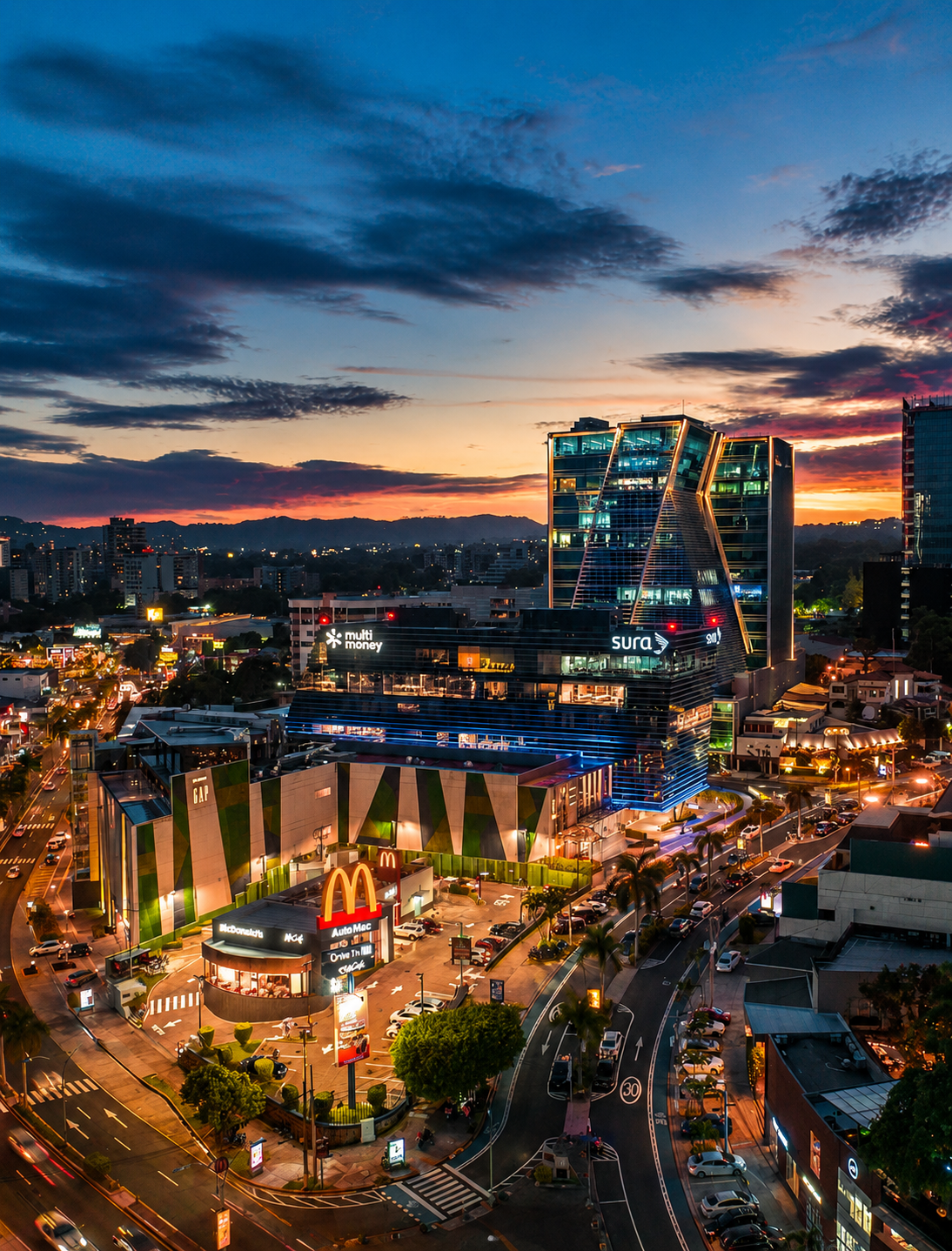 Vista aérea del paisaje urbano al atardecer de san benito con rascacielos iluminados y una concurrida plaza de McDonald's