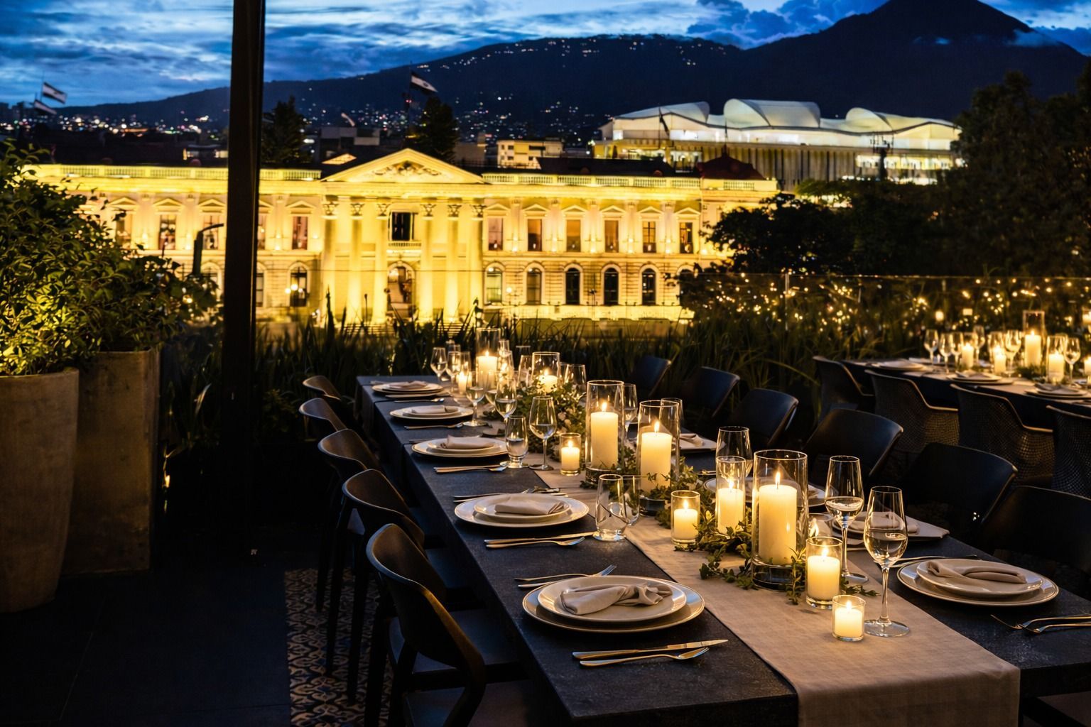 Elegante terraza en la azotea con luces centelleantes, sillas negras y mesas iluminadas con velas, con vistas a la ciudad por la noche.