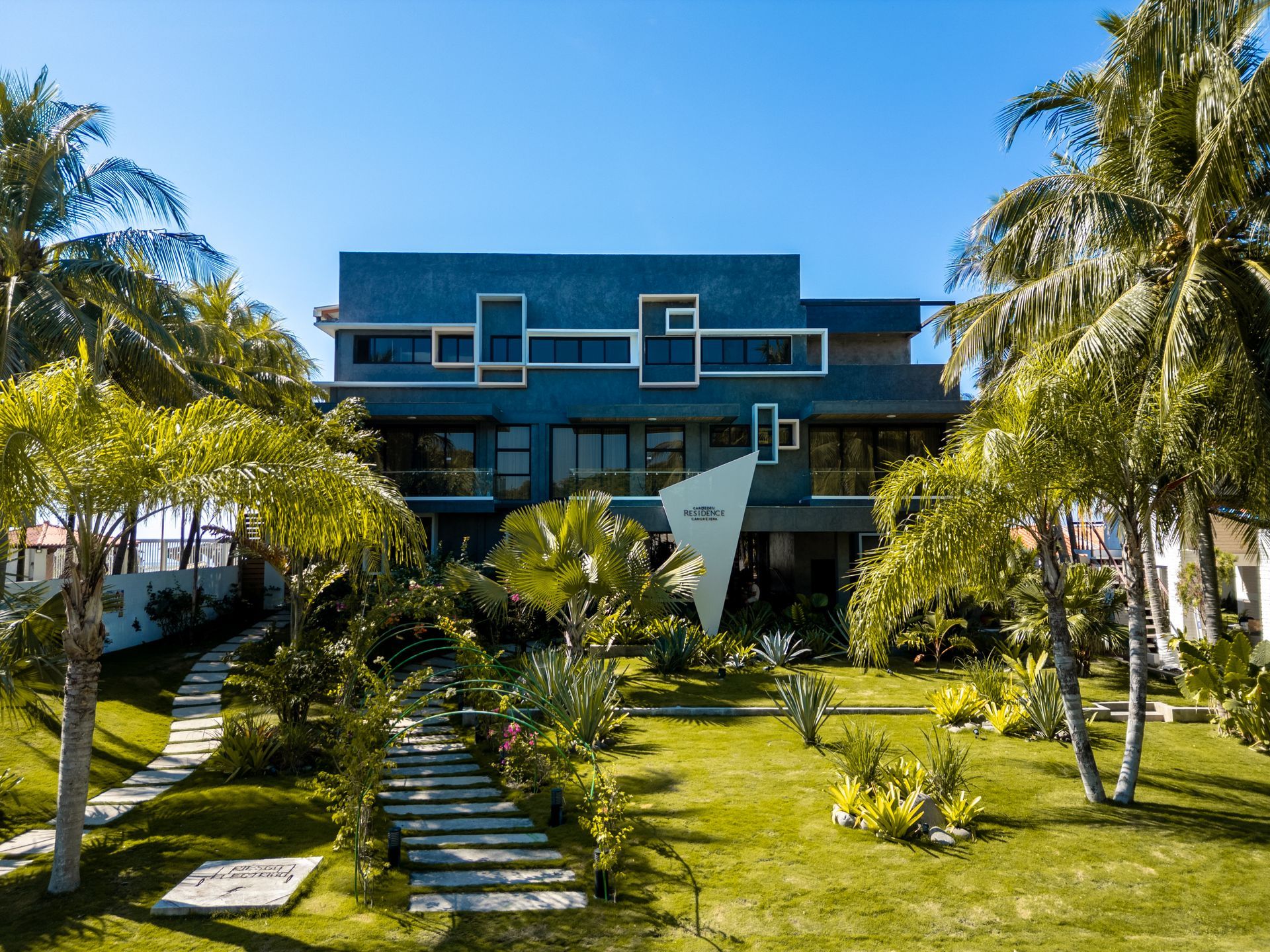 Cardedeu cangrejera la libertad el salvador frente a la playa con un edificio azul, palmeras y un paseo ajardinado en la entrada.