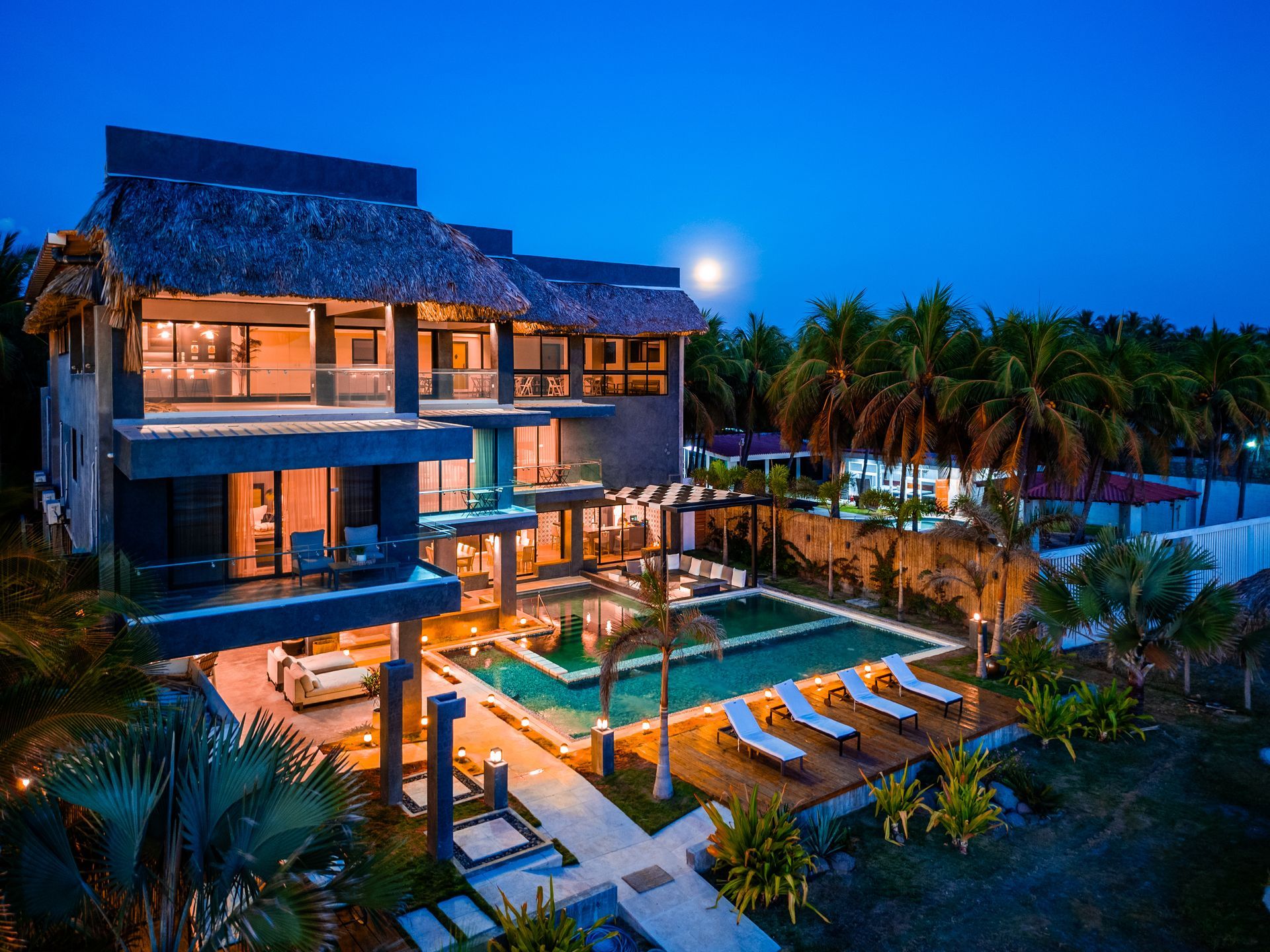 Hotel cardedeu cangrejera la libertad el salvador frente al mar con piscina iluminada y palmeras al atardecer.